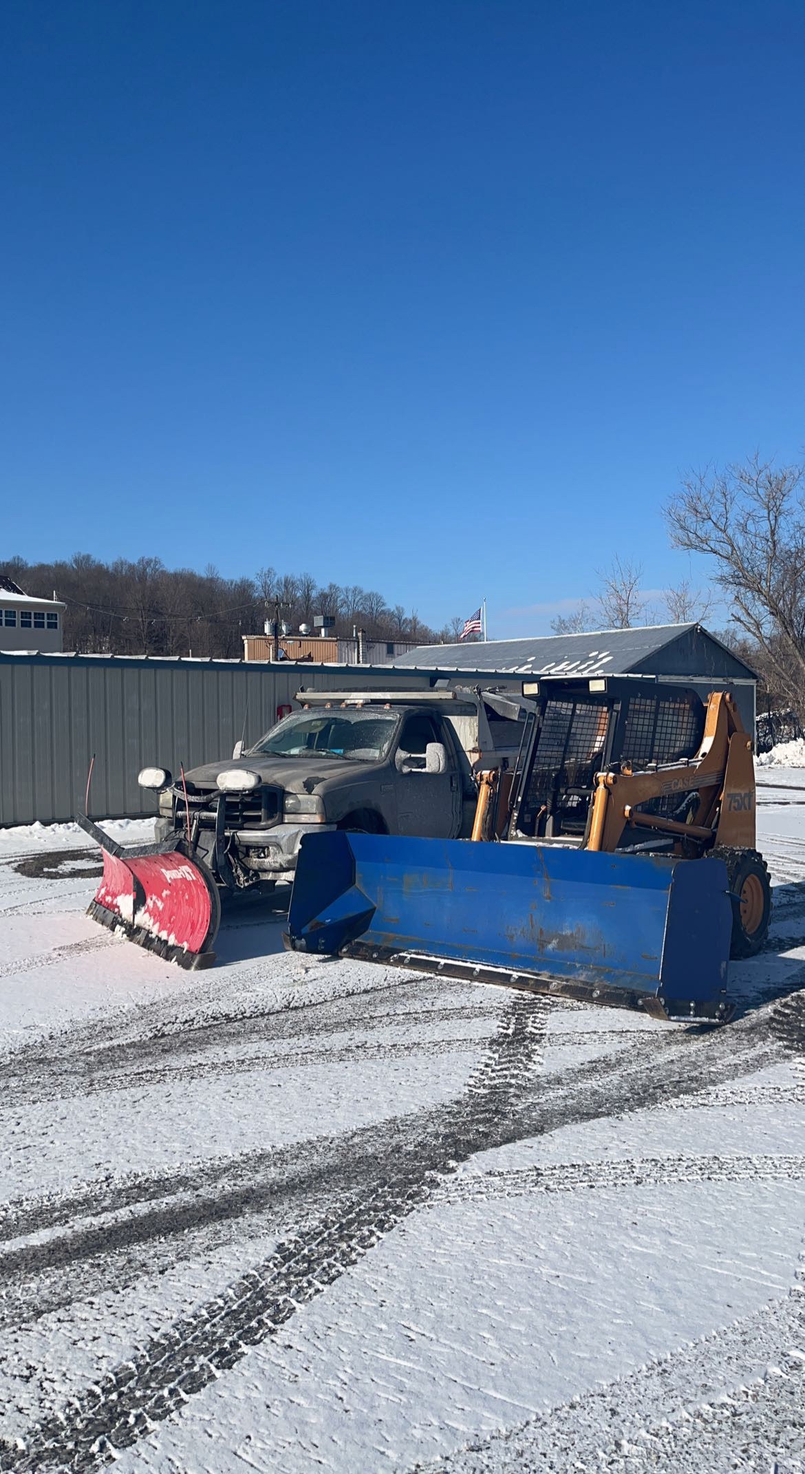 JRW Services skid steer with a snow pusher attachment on a clear day