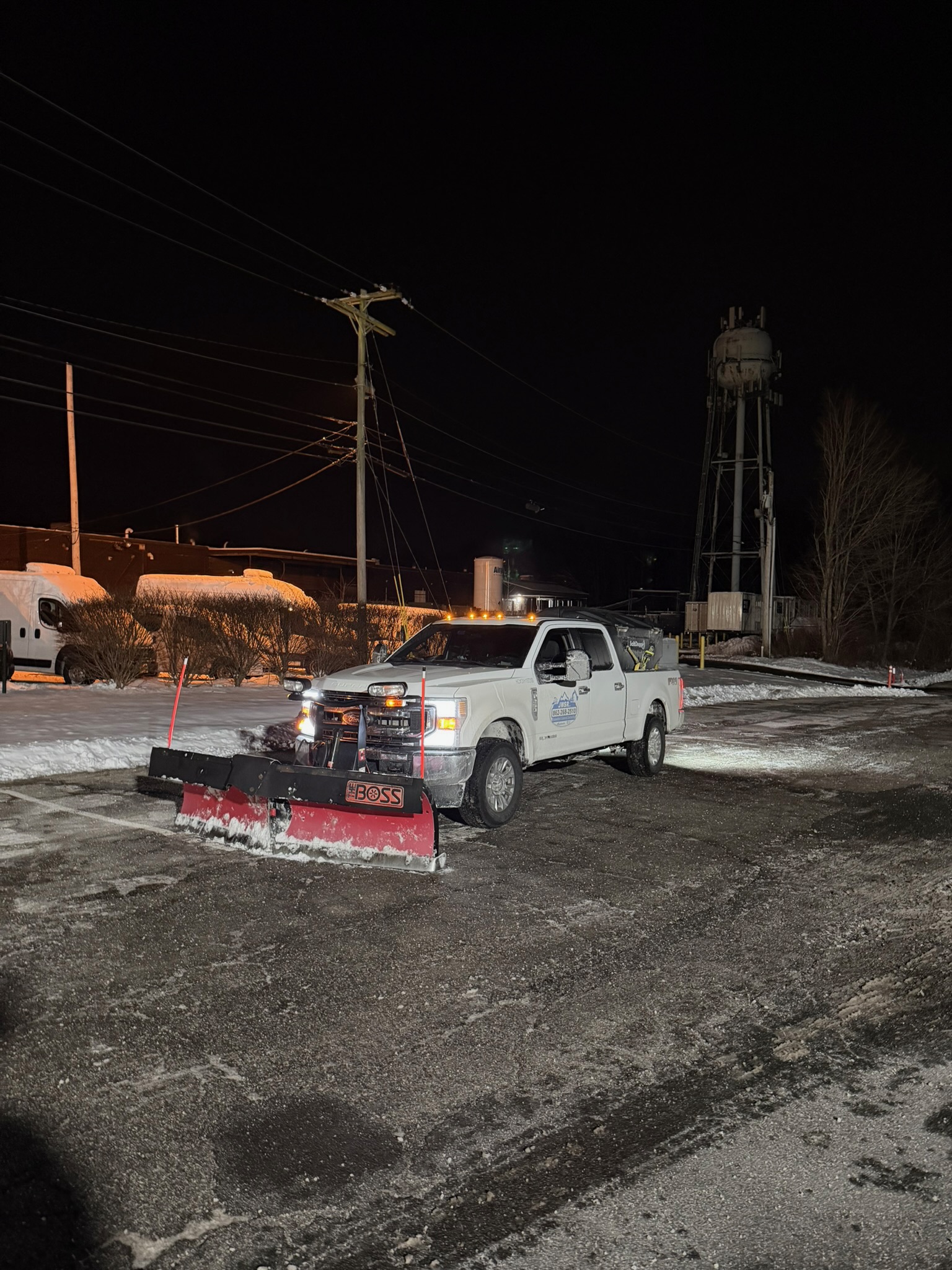 JRW Services plow truck staged at night with a water tower in the background